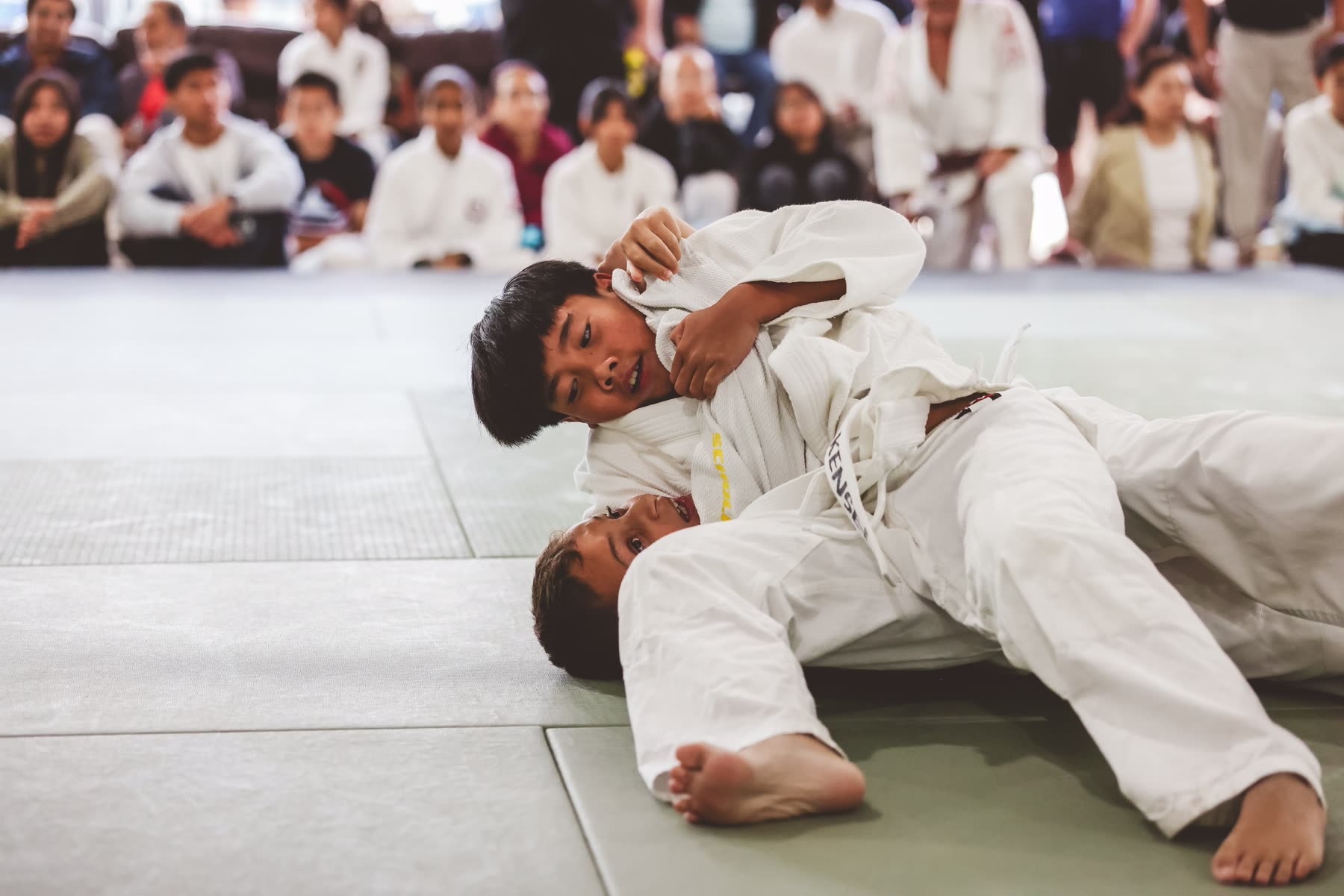 Two young Kensei students laughing together on the mat